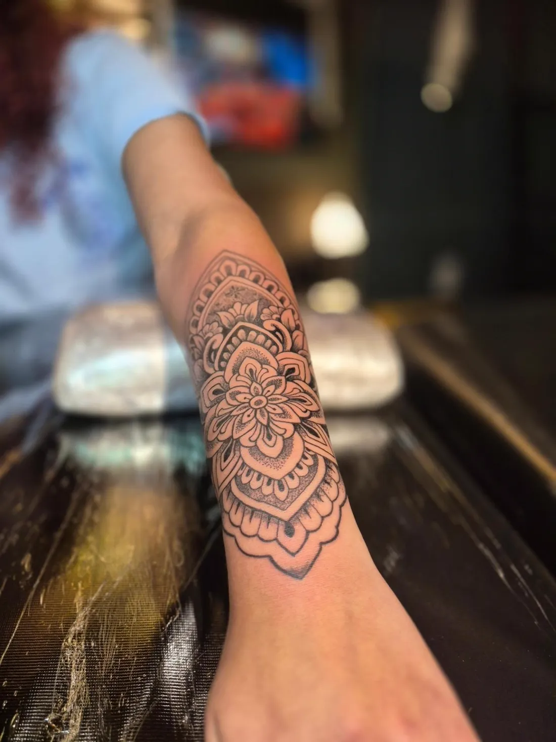 Tatuagem de mandala floral recém-finalizada, fotografada no balcão de madeira do Ateliê Garden