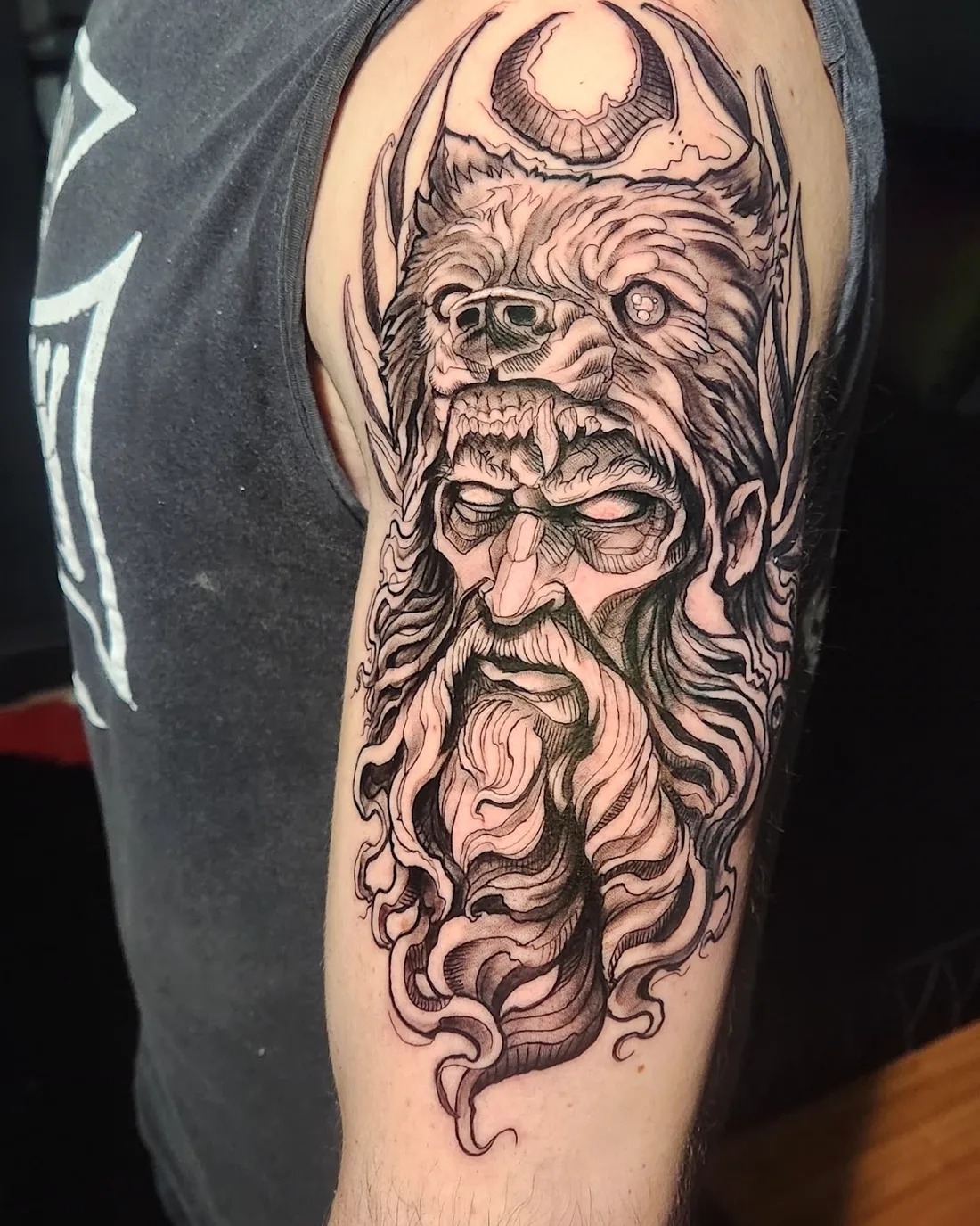 Tatuagem autoral em fine line feita no Ateliê Garden, retratando um rosto encapuzado detalhado no braço de um cliente